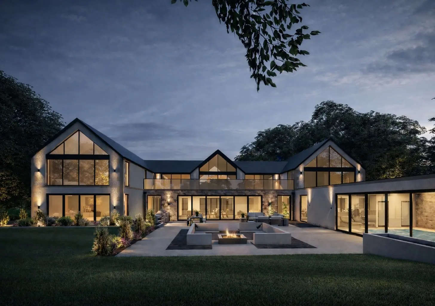The rear elevation at dusk, interiors lit, sunken fire terrace in the foreground